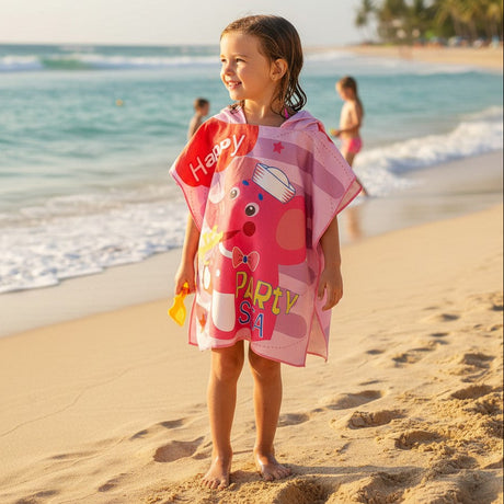Girl on the beach wearing a pink hooded poncho towel with a cartoon elephant print