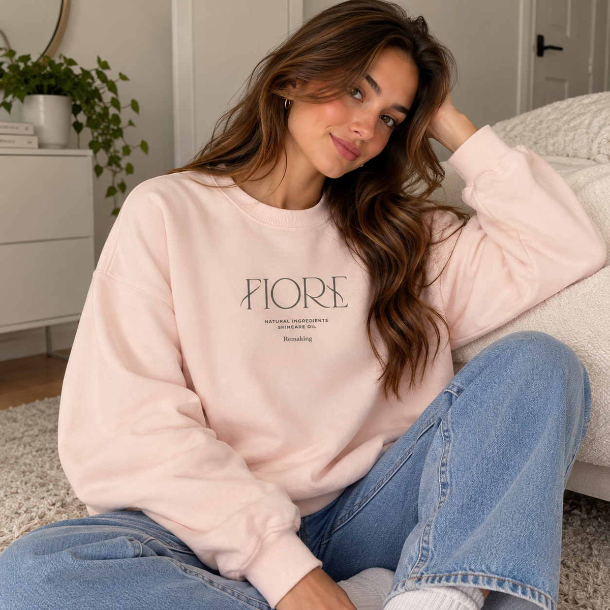Woman in a pink crew neck sweatshirt with minimalist Fiore lettering, worn with light jeans