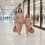 Mother and daughter in matching pink teddy fleece hoodie sets, holding hands while shopping