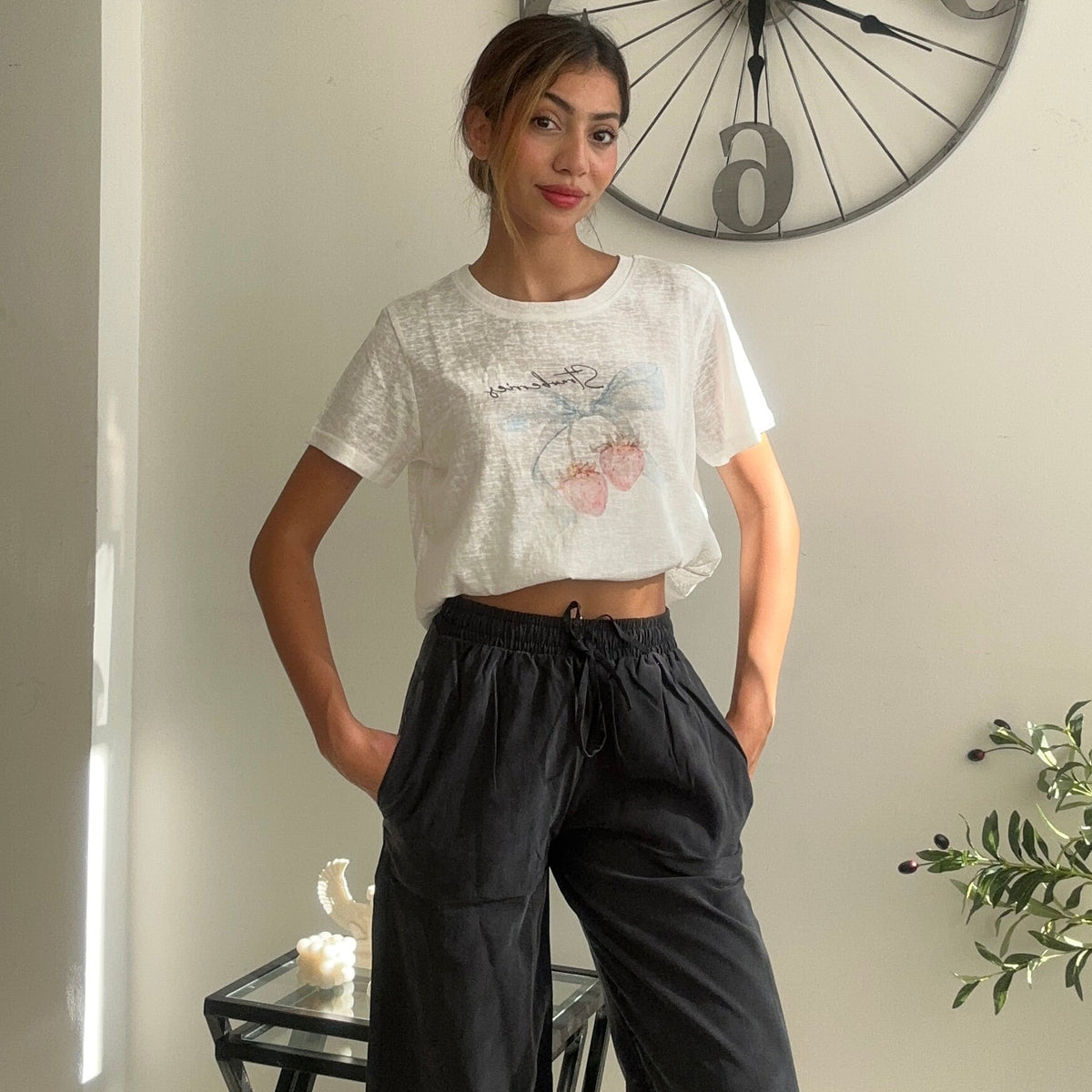 Pink floral print crop tee styled with charcoal trousers in a sunlit room