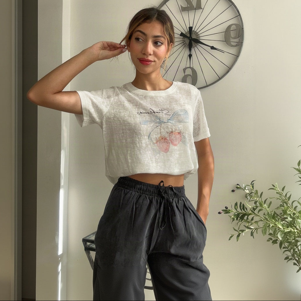White crop tee with a pink floral print worn with charcoal wide leg trousers