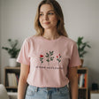 Woman wearing a pink tshirt with floral design and text in a room with plants and books