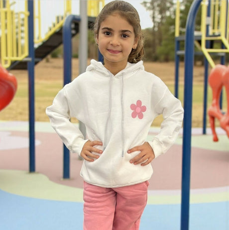White hoodie with a pink daisy on the chest worn with pink joggers at a playground