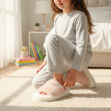 Girl in pyjamas kneeling on a rug wearing a pink fluffy slipper