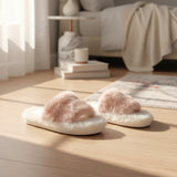 Pale pink faux fur cross strap slippers with a cream sole on a wooden floor