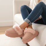 Dusty rose platform mules with a pale blush fur collar, ankles crossed on a sofa