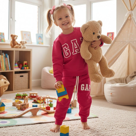 Fuchsia pink girls jogging set with a logo sweatshirt and matching joggers, holding a teddy