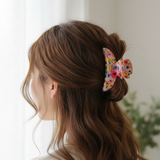 Bright pink and purple floral claw clip holding a half up bun