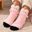 Pink fuzzy socks with googly eyes, little 3D arms and legs, a black toe and a fluffy cream cuff