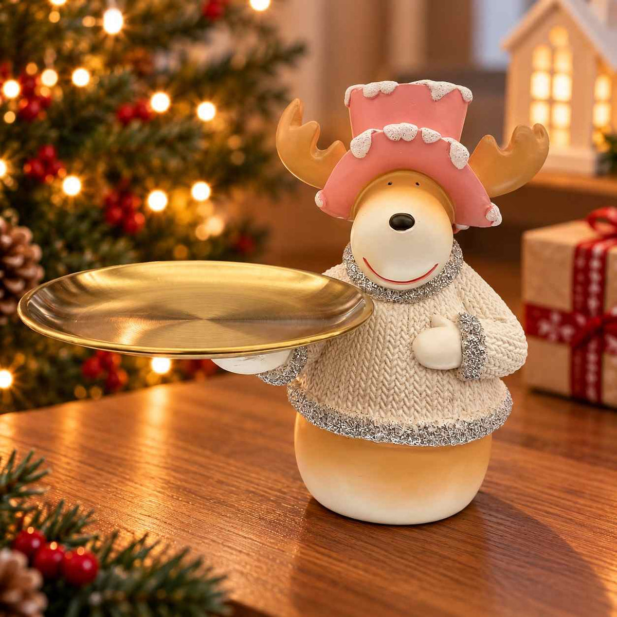Reindeer figurine in a pink frosted top hat and cream sweater holding a round golden tray