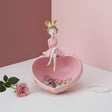 Baby pink heart dish holding keys, a gold chain and pearls, a polka dot girl on the rim