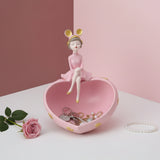 Baby pink heart dish holding keys, a gold chain and pearls, a polka dot girl on the rim