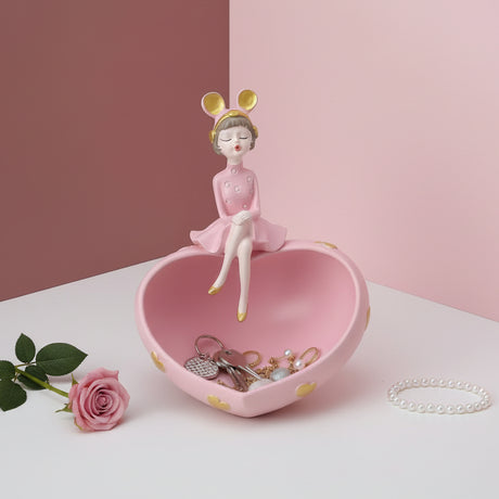 Baby pink heart dish holding keys, a gold chain and pearls, a polka dot girl on the rim