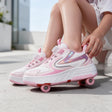 Pink and white roller shoes with a twist dial and holographic side panel, worn outdoors on concrete
