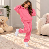 Girl in a hot pink fleece hoodie and matching joggers posing on one leg by a teddy bear