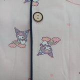 Button placket close up with navy piping and cartoon character rainbow print on pale pink fabric