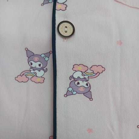 Button placket close up with navy piping and cartoon character rainbow print on pale pink fabric