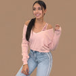 Pink V neck knit sweater falling off one shoulder, strappy cami layer underneath