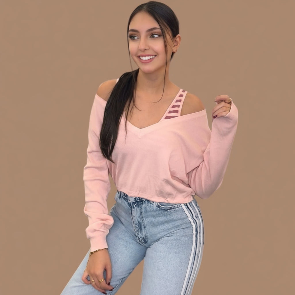 Pink V neck knit sweater falling off one shoulder, strappy cami layer underneath