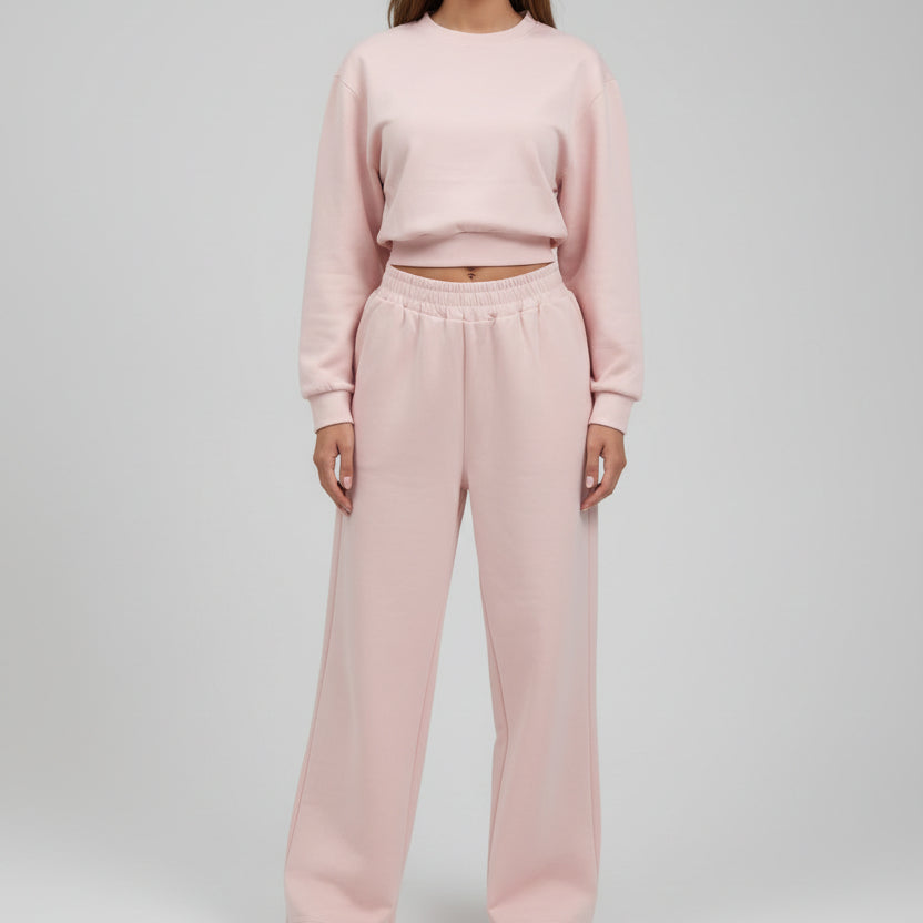 Pale pink set photographed from the neck down against a plain wall