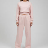 Pale pink set photographed from the neck down against a plain wall