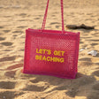 Pink woven Lets Get Beaching tote bag on the sand, Jack Gifts Online Lebanon