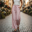Person wearing pink pants and a white top on a cobblestone street with blurred flower in the background
