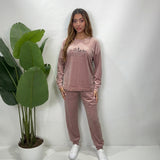 Woman in a dusty pink velvet PJ set with a London skyline print top and jogger pants