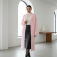 Woman wearing a pink long coat in a minimalistic room