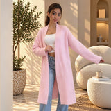 Long pastel pink knit coat cardigan worn open over a white top and jeans