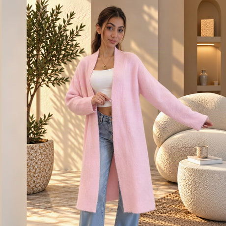 Long pastel pink knit coat cardigan worn open over a white top and jeans