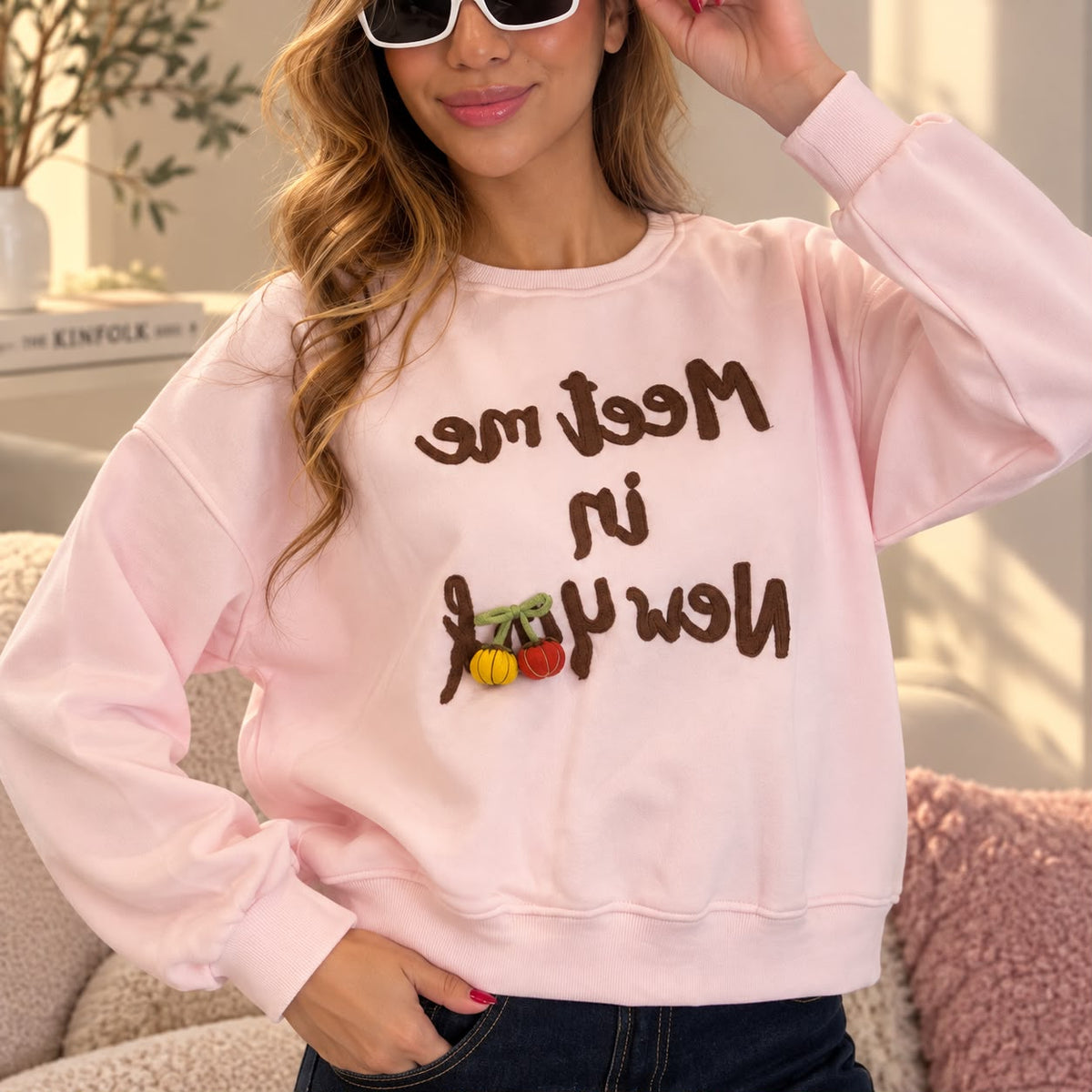 Closer view of the pink sweatshirt with brown chain stitch lettering and padded cherry charms