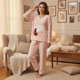 Pale pink fleece pyjama set with a smiling cloud and sleepy moon applique, worn standing in a living room
