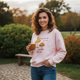 Woman wearing a soft pink sweatshirt with golden embroidered mushrooms and rust lettering