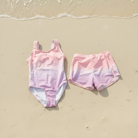 Pink ombre tankini and shorts flat lay on sand