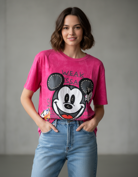 Woman wearing a pink tshirt with a cartoon character design against a plain background
