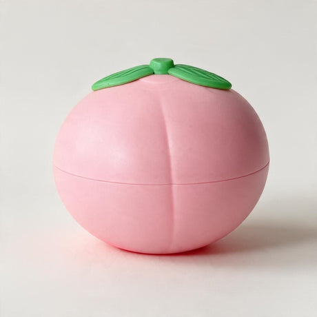 Round pink peach squishy with a centre crease and green leaves on top