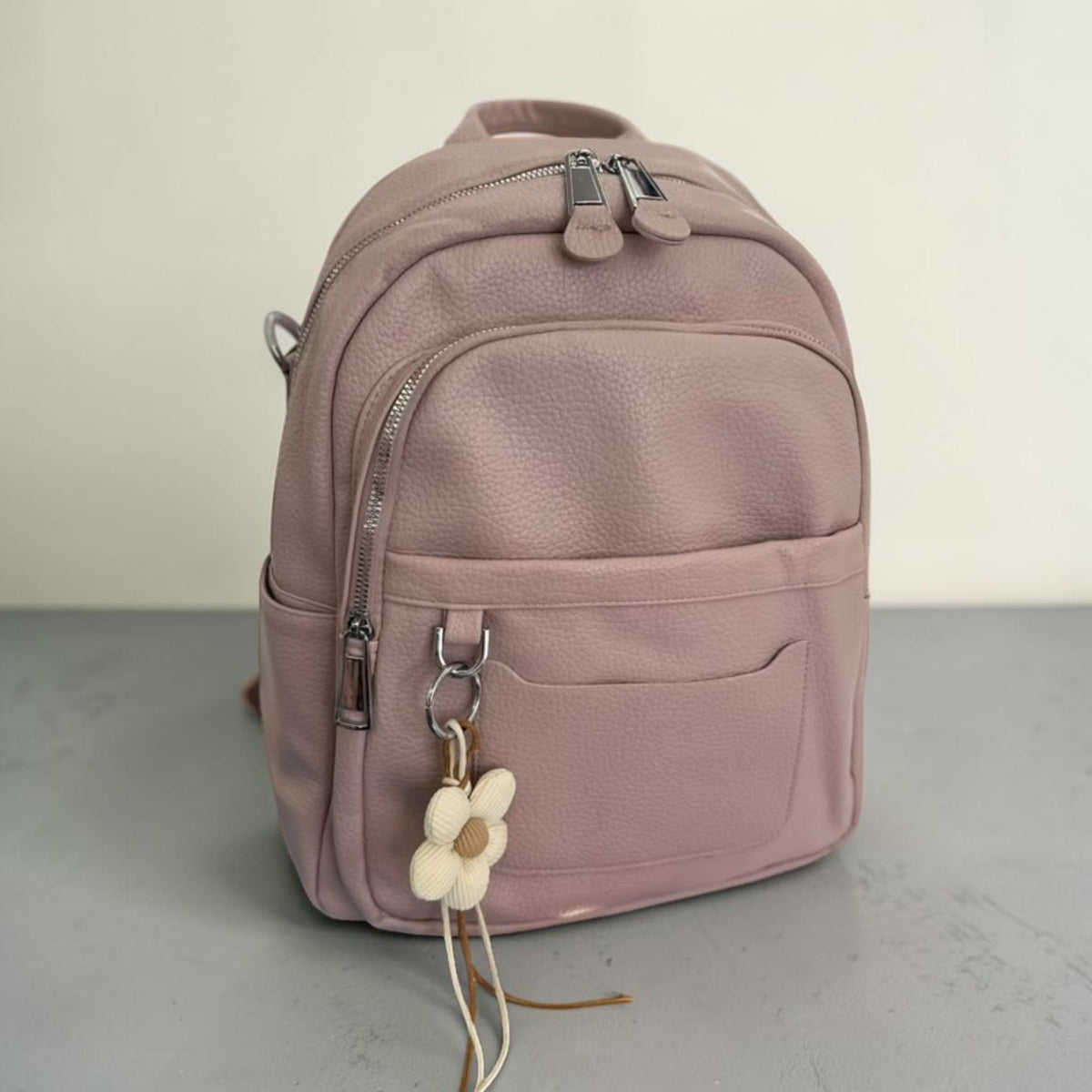 Dusty pink pebbled faux leather backpack with a cream beaded flower charm