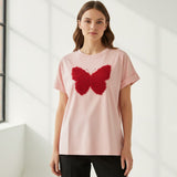 Woman wearing a pink tshirt with a red butterfly design in a minimalistic setting