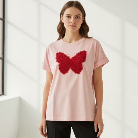 Woman wearing a pink tshirt with a red butterfly design in a minimalistic setting