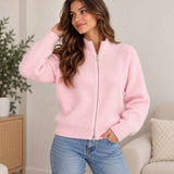 Woman in a pink ribbed knit zip up cardigan with a funnel neck and light blue jeans