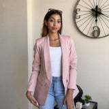 Pink blazer layered over a white ribbed vest with high waisted blue jeans