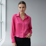 Woman wearing a bright pink silk shirt against a neutral background