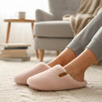 Blush boucle mules with a high wrapping vamp and cream collar, worn in a grey armchair