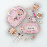 Pink makeup pouches with 'Hello Spring' text, surrounded by cosmetic items on a light grey background