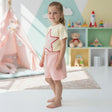Girl in a cream star outline tee and soft pink shorts