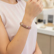 Person wearing a pink bracelet with star designs in a store setting