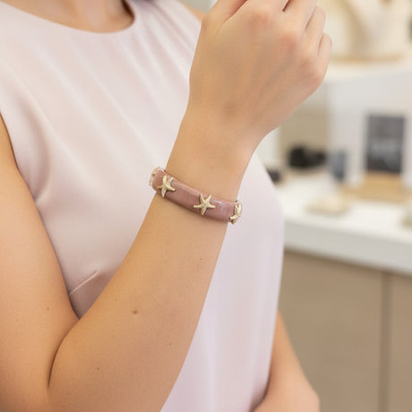 Person wearing a pink bracelet with star designs in a store setting