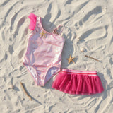 Pink starfish swimsuit and tulle skirt flat lay with shell props