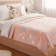Pink fleece blanket with pastel stars spread over a bed